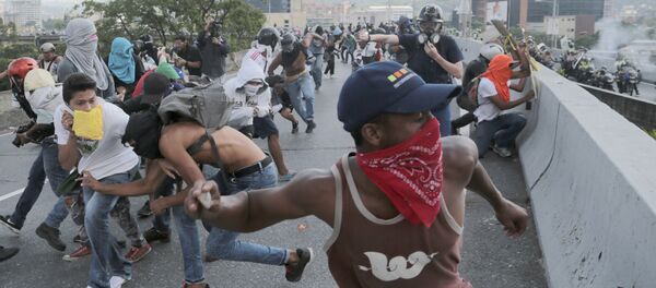 Anti-government protesters throw stones from a highway overpass at a passing police patrol in Caracas, Venezuela, Monday, April 24, 2017 - Sputnik International