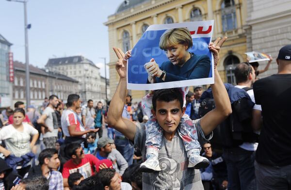 A man holds up a poster of German Chacellor Angela Merkel before starting a march out of Budapest, Hungary, Friday, Sept. 4, 2015 A man holds up a poster of German Chacellor Angela Merkel before starting a march out of Budapest, Hungary, Friday, Sept. 4, 2015 - Sputnik International