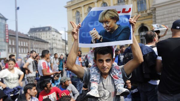 A man holds up a poster of German Chacellor Angela Merkel before starting a march out of Budapest, Hungary, Friday, Sept. 4, 2015 - Sputnik International