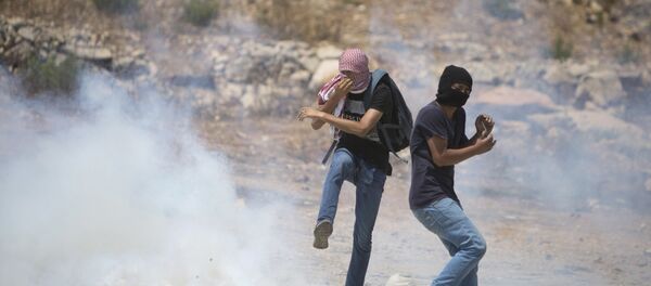 Palestinian protesters react to a tear gas canister fired by Israeli troops during a protest with solidarity hunger strike of Palestinian prisoners in the Israeli jails - Sputnik International