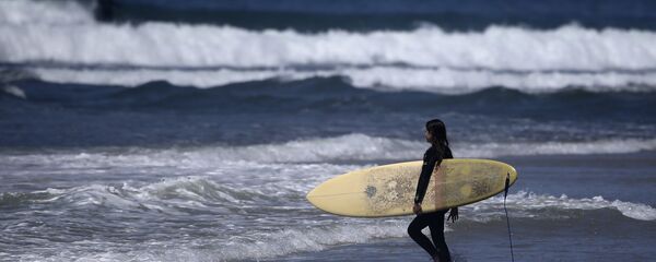 A surfer strolls into the waves at Cardiff State Beach in Encinitas, Calif. - Sputnik International