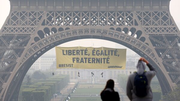 Tourists walk at Trocadero square as activists from the environmentalist group Greenpeace unfurl a giant banner on the Eiffel Tower which reads Liberty, Equality, Fraternity in a call on French citizens to vote against the National Front (FN) presidential candidate Marine Le Pen, in Paris, France May 5, 2017 - Sputnik International