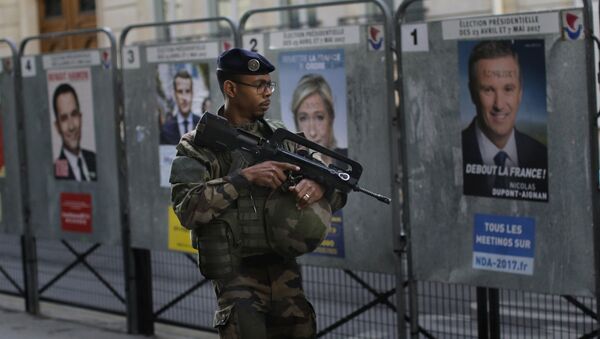 An army soldier patrols past posters showing faces of the candidates for the first-round presidential election near a polling station in Paris, Sunday, April 23, 2017 - Sputnik International