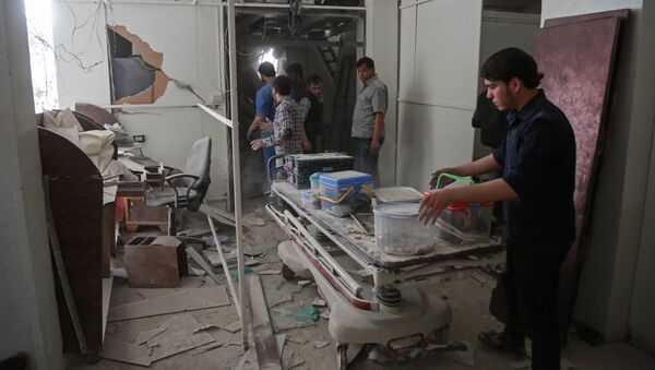 Syrians salvage medical items from a hospital following an air strike a rebel-controlled town in the eastern Ghouta region on the outskirts of the capital Damascus on May 1, 2017 - Sputnik International