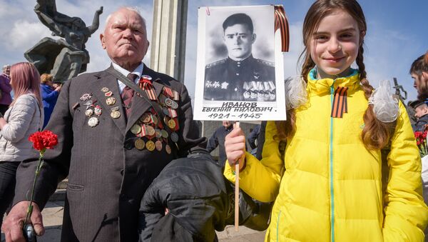 A World War II veteran and a girl attend festivities at the Victory Monument as Latvia's large Russian minority marks 72 years since the end of World War II and commemorates the Soviet victory over Nazi Germany in Riga, Latvia - Sputnik International