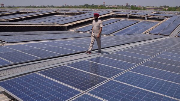 An Indian security personnel poses for media as he walks over rooftops covered in solar panels at the Solar Photovoltaic Power Plant, some 45kms from Amritsar. (File) - Sputnik International