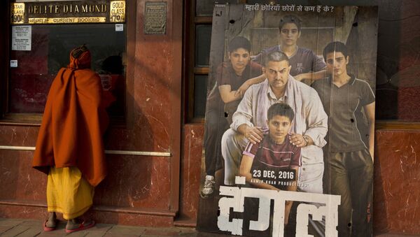 An Indian Sadhu, or Hindu holy man, buys a movie ticket at a counter beside a poster of Bollywood movie Dangal, a 2016 biopic on an Indian wrestling coach and his two professional wrestler daughters, outside a theater in New Delhi, India, Tuesday, Jan. 17, 2017 - Sputnik International