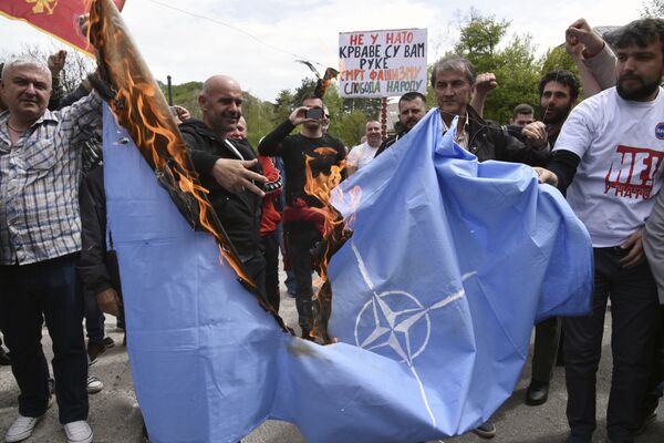 Anti-NATO demonstrators burn a NATO flag in front of a a banner that reads: No to NATO, your hands are bloody - Death to fascism, freedom to the people, during a protest outside the hall before the parliament session in Cetinje, Montenegro, Friday, April 28, 2017 Anti-NATO demonstrators burn a NATO flag in front of a a banner that reads: No to NATO, your hands are bloody - Death to fascism, freedom to the people, during a protest outside the hall before the parliament session in Cetinje, Montenegro, Friday, April 28, 2017 - Sputnik International