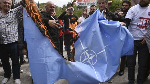 Anti-NATO demonstrators burn a NATO flag in front of a a banner that reads: No to NATO, your hands are bloody - Death to fascism, freedom to the people, during a protest outside the hall before the parliament session in Cetinje, Montenegro, Friday, April 28, 2017 - Sputnik International