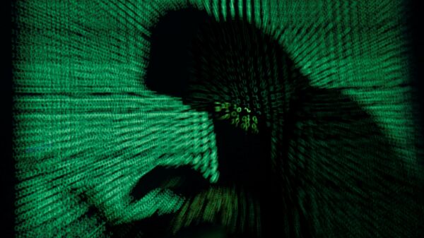 A hooded man holds a laptop computer as cyber code is projected on him in this illustration picture taken on 13 May 2017 - Sputnik International