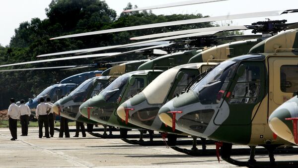Officials walk past a line of parked Dhruv helicopters of India's Hindustan Aeronautics Ltd. (HAL) standing on the tarmac at The HAL helicopter division in Bangalore - Sputnik International