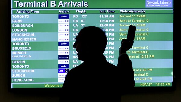 A person points to a screen with an airplane travel list while holding up a phone at Newark Liberty International Airport, in Newark, N.J. - Sputnik International