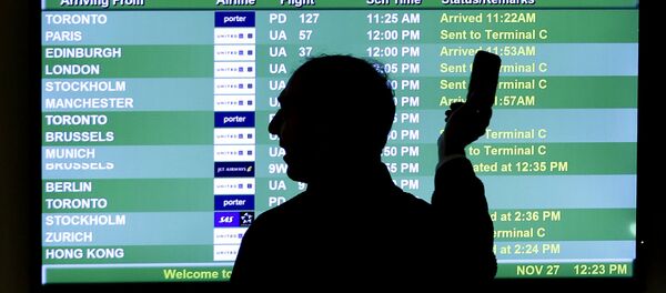 A person points to a screen with an airplane travel list while holding up a phone at Newark Liberty International Airport, in Newark, N.J. A person points to a screen with an airplane travel list while holding up a phone at Newark Liberty International Airport, in Newark, N.J. - Sputnik International