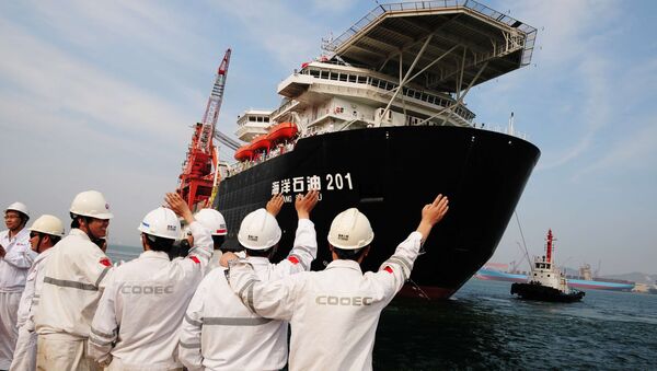 Chinese port workers wave as China National Offshore Oil Corp. (CNOOC)'s first independent deep-water oil drilling rig, was sent off from the port of Qingdao, east China's Shandong province. China's first home-grown deep-water drilling rig will be located in the South China Sea, some 300 kilometres (200 miles) southeast of Hong Kong - Sputnik International