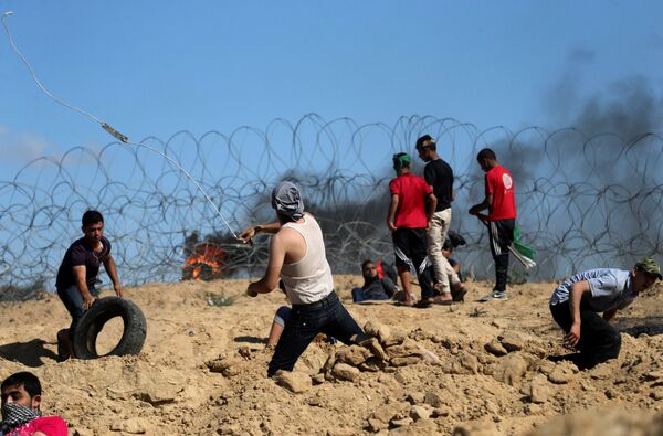 Palestinian protesters hurl stones at Israeli troops following a protest against the blockade on Gaza, near the border between Israel and Central Gaza Strip May 19, 2017 - Sputnik International