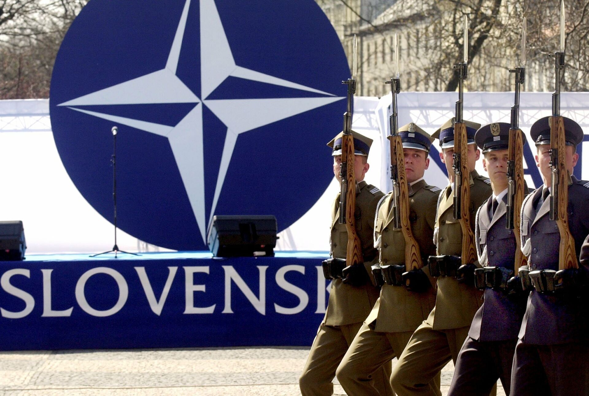 Members of a honor guard present arms in front of the NATO logo during a ceremony to mark the country's entry into the military alliance on Friday, April 2, 2004 in Bratislava - Sputnik International, 1920, 09.04.2022