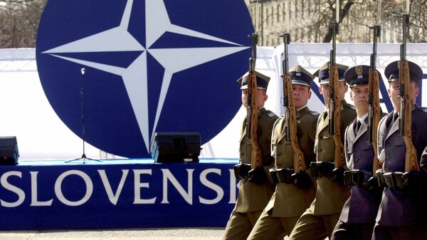 Members of a honor guard present arms in front of the NATO logo during a ceremony to mark the country's entry into the military alliance on Friday, April 2, 2004 in Bratislava - Sputnik International