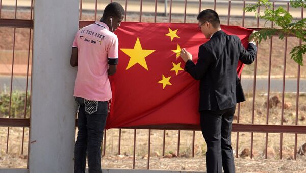 A Senegalese worker and a Chinese man put a Chinese flag in Diamniadio district in Dakar on May 7, 2017 during the visit of Chinese vice president Li Yuanchao (not seen) - Sputnik International
