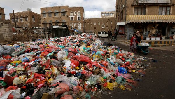 A girl pushes a wheel cart with water jerrycans past a pile of rubbish bags on a street during a strike by garbage collectors demanding delayed salaries in Sanaa, Yemen May 8, 2017 - Sputnik International