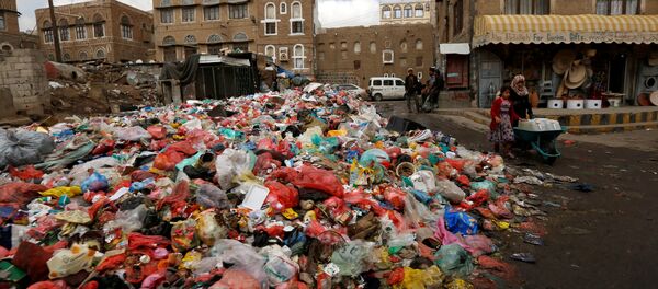 A girl pushes a wheel cart with water jerrycans past a pile of rubbish bags on a street during a strike by garbage collectors demanding delayed salaries in Sanaa, Yemen May 8, 2017 - Sputnik International