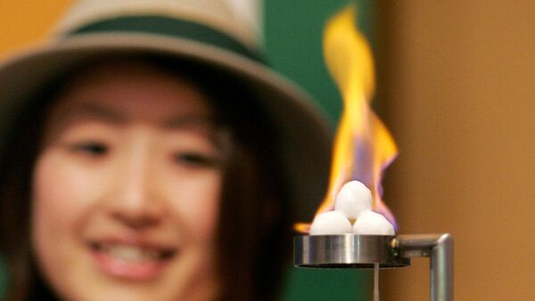 Attendant of Japan's Gas Pavilion introduces an experiment of the burning ice, methane hydrate, as a potential future source of energy during a press preview for the 2005 World Exposition in Nagakute, Aichi prefecture, 19 March 2005 - Sputnik International