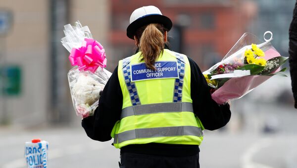 A community support officer carries flowers near Manchester Arena in Manchester, Britain May 24, 2017. - Sputnik International