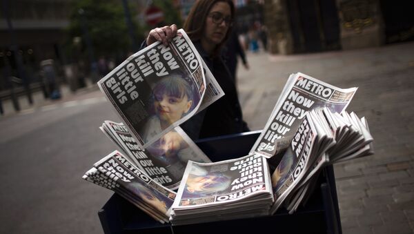 A woman picks a newspaper reporting the news on the suicide attack at a concert by Ariana Grande that killed more than 20 people as it ended Monday night in central Manchester, Britain, Wednesday, May 24, 2017. - Sputnik International