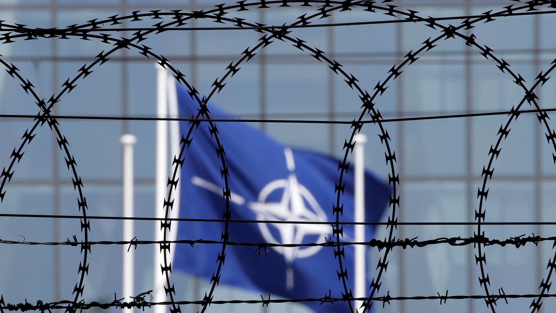 The NATO flag is seen through barbed wire as it flies in front of the new NATO Headquarters in Brussels, Belgium May 24, 2017 - Sputnik International, 1920, 15.06.2021