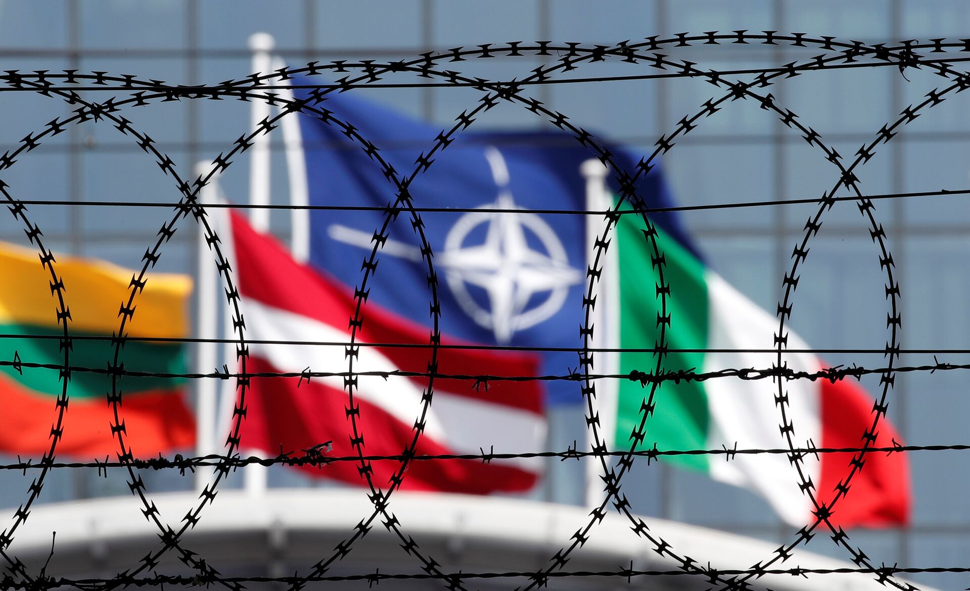 The NATO flag is seen through barbed wire as it flies in front of the new NATO Headquarters in Brussels, Belgium May 24, 2017 - Sputnik International, 1920, 13.11.2021