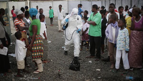 In this file photo daetd Tuesday, Sept. 30, 2014, a medical worker sprays people being discharged from the Island Clinic Ebola treatment center in Monrovia, Liberia - Sputnik International