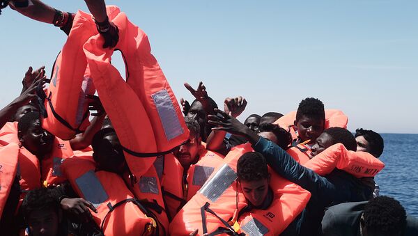 Migrants in an overcrowded plastic raft reach out for life jackets during a search and rescue operation by rescue ship Aquarius, operated by SOS Mediterranean and Doctors without Borders, in central Mediterranean Sea May 18, 2017 - Sputnik International