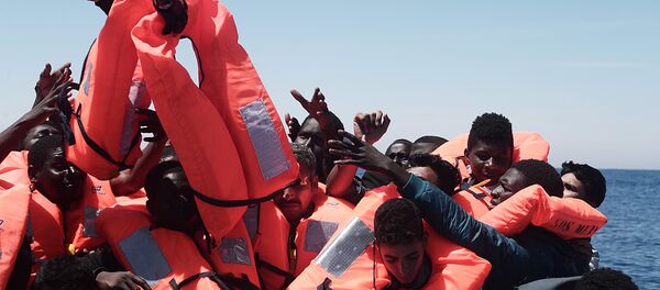 Migrants in an overcrowded plastic raft reach out for life jackets during a search and rescue operation by rescue ship Aquarius, operated by SOS Mediterranean and Doctors without Borders, in central Mediterranean Sea May 18, 2017 Migrants in an overcrowded plastic raft reach out for life jackets during a search and rescue operation by rescue ship Aquarius, operated by SOS Mediterranean and Doctors without Borders, in central Mediterranean Sea May 18, 2017 - Sputnik International