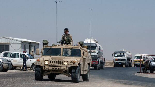 A convoy of fuel tanker trucks escorted by a US Army vehicle enter Kuwait at the military border post of Abdaly in the Kuwait-Iraq frontier in this file photo taken January 2006 - Sputnik International