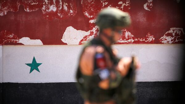 A Russian soldier stands guard near a Syrian national flag drawn on the wall as rebel fighters and their families evacuate the besieged Waer district in the central Syrian city of Homs, after an agreement reached between rebels and Syria's army, Syria May 21, 2017 - Sputnik International