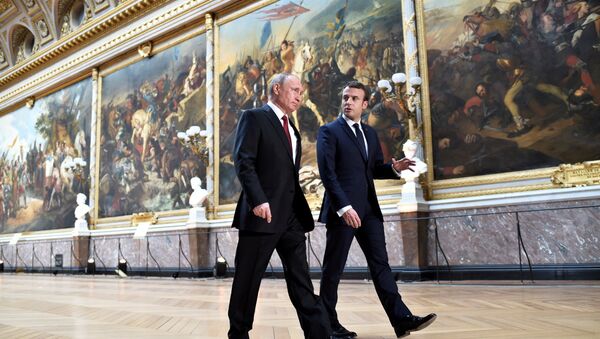 French President Emmanuel Macron (R) speaks to Russian President Vladimir Putin (L) in the Galerie des Batailles (Gallery of Battles) as they arrive for a joint press conference at the Chateau de Versailles before the opening of an exhibition marking 300 years of diplomatic ties between the two countries in Versailles, France, May 29, 2017 - Sputnik International