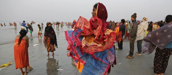 A woman holds saris of companions taking holy dips at the confluence of the Bay of Bengal and Ganges River on Makar Sankranti festival in Gangasagar, India, Saturday, Jan. 14, 2017 A woman holds saris of companions taking holy dips at the confluence of the Bay of Bengal and Ganges River on Makar Sankranti festival in Gangasagar, India, Saturday, Jan. 14, 2017 - Sputnik International