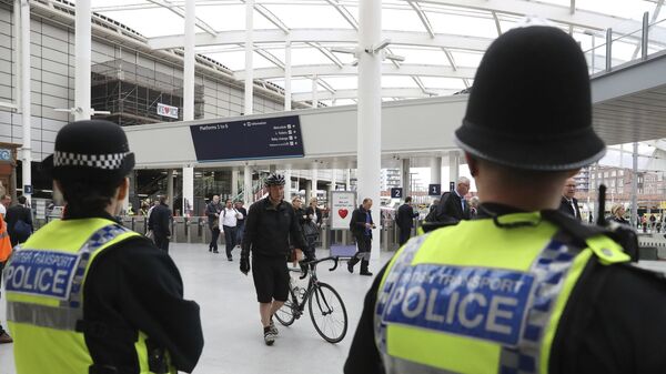 Police watch as commuters pass through Manchester Victoria railway station in Manchester England, which has reopened for the first time since the terror attack on the adjacent Manchester Arena Tuesday May 30, 2017 - Sputnik International