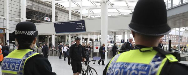 Police watch as commuters pass through Manchester Victoria railway station in Manchester England, which has reopened for the first time since the terror attack on the adjacent Manchester Arena Tuesday May 30, 2017 - Sputnik International
