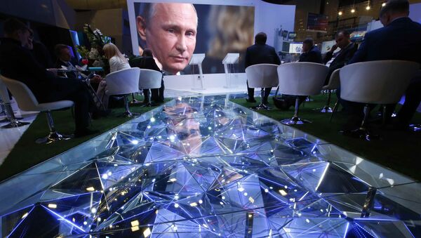 Participants of the St. Petersburg International Economic Forum (SPIEF) sit near an electronic screen showing Russian President Vladimir Putin, who attends a session of the forum in St. Petersburg, Russia, June 2, 2017 - Sputnik International