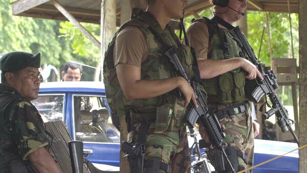Two U.S. Army Special Forces clutch their M4 carbine beside their Filipino counterpart as they man a checkpoint at the entry of a military base - Sputnik International