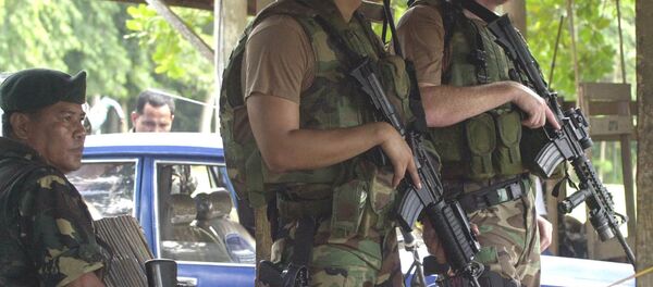 Two U.S. Army Special Forces clutch their M4 carbine beside their Filipino counterpart as they man a checkpoint at the entry of a military base - Sputnik International