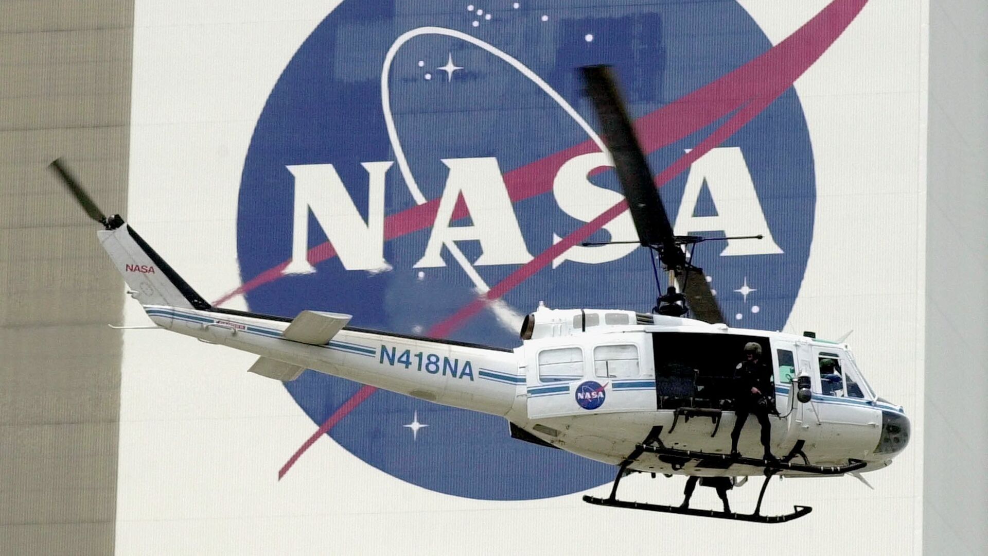  A NASA security helicopter flies by the NASA logo on the Vehicle Assembly Building - Sputnik International, 1920, 14.09.2023