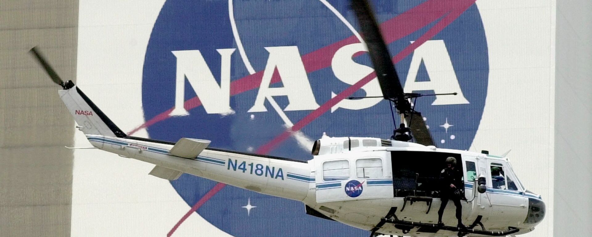 A NASA security helicopter flies by the NASA logo on the Vehicle Assembly Building - Sputnik International, 1920, 22.06.2017
