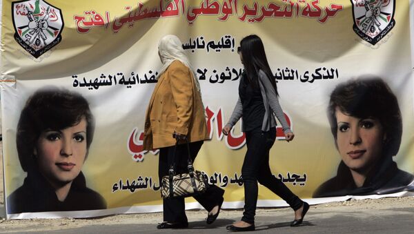 Palestinian women walk past a banner in the West bank town of Bireh, which pictures Fatah member Dalal Mughrabi, who led an attack on an Israeli bus near Tel Aviv, killing 36 people in 1978 - Sputnik International