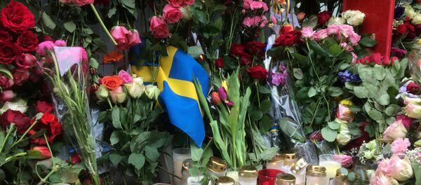 Sweden's flag is seen among flowers near the crime scene in central Stockholm April 8, 2017, the day after a hijacked beer truck plowed into pedestrians on Drottninggatan and crashed into Ahlens department store. Sweden's flag is seen among flowers near the crime scene in central Stockholm April 8, 2017, the day after a hijacked beer truck plowed into pedestrians on Drottninggatan and crashed into Ahlens department store. - Sputnik International