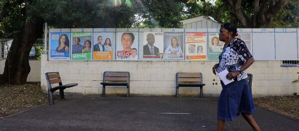 A woman walks past campaign posters as she arrives to a polling station in La Possession on the French Indian Ocean island of La Reunion during the first round of the French legislative elections on June 11, 2017 A woman walks past campaign posters as she arrives to a polling station in La Possession on the French Indian Ocean island of La Reunion during the first round of the French legislative elections on June 11, 2017 - Sputnik International