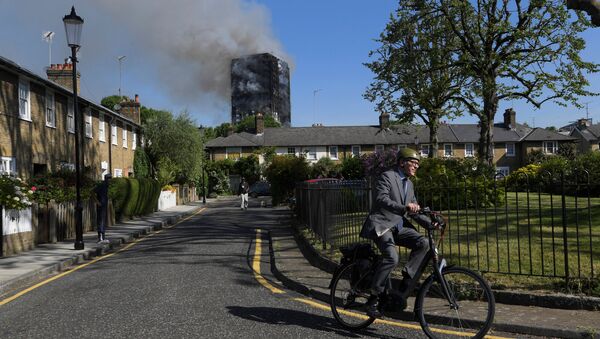 A cyclist rides near a tower block severly damaged by a serious fire, in north Kensington, West London, Britain June 14, 2017 - Sputnik International