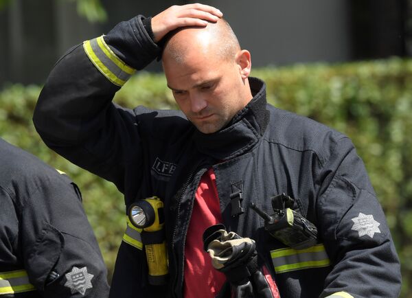 Firefighters rest near a tower block, severely damaged in a serious fire, in north Kensington, West London, Britain June 14, 2017. Firefighters rest near a tower block, severely damaged in a serious fire, in north Kensington, West London, Britain June 14, 2017. - Sputnik International