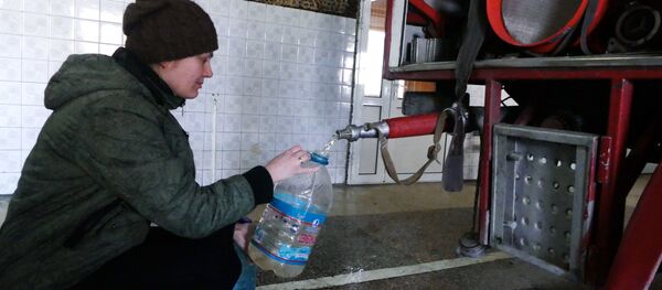 A woman in the Kievsky district of Donetsk gathers process water at the fire station after shelling A woman in the Kievsky district of Donetsk gathers process water at the fire station after shelling - Sputnik International