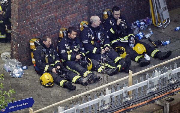 Firefighters rest as they take a break in battling a massive fire that raged in a high-rise apartment building in London, Wednesday, June 14, 2017. - Sputnik International